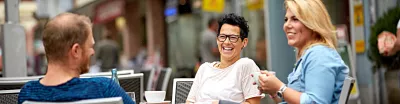 Mann und Frauen im Straßencafé, Lachen